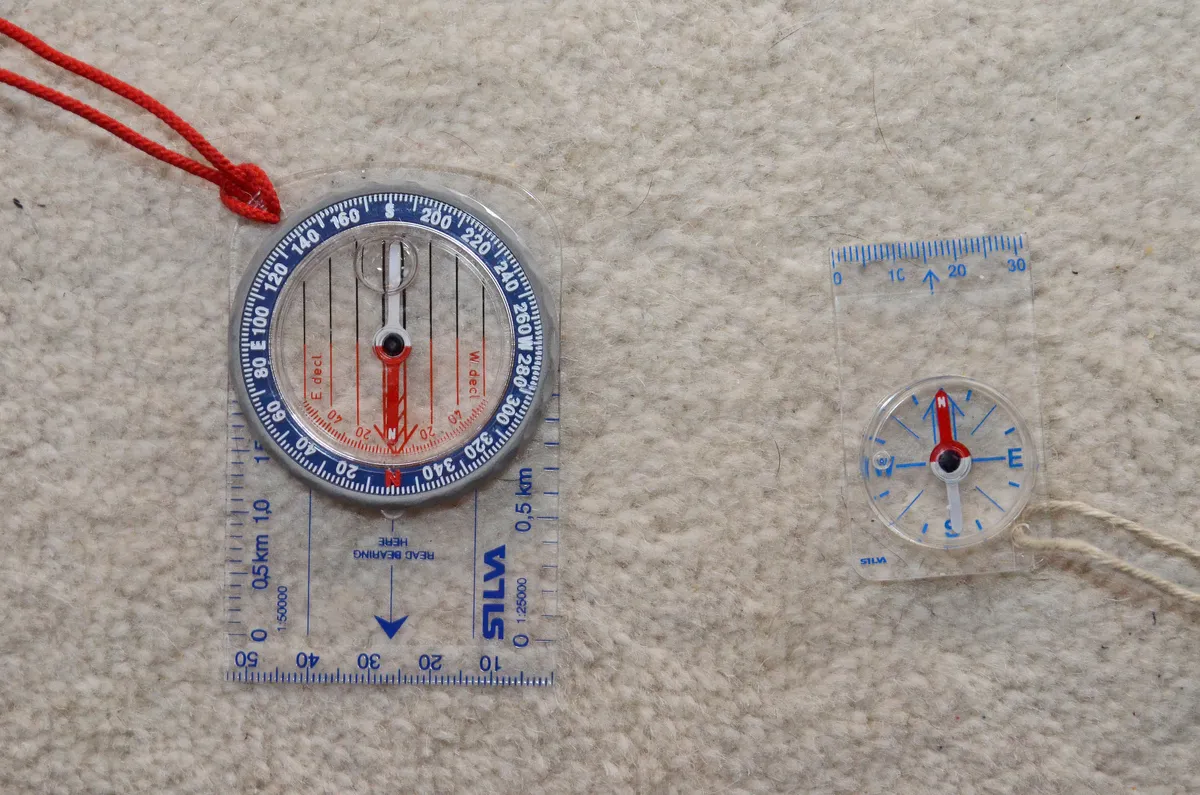 A full-size baseplate compass beside a small keyring compass, showing the size difference