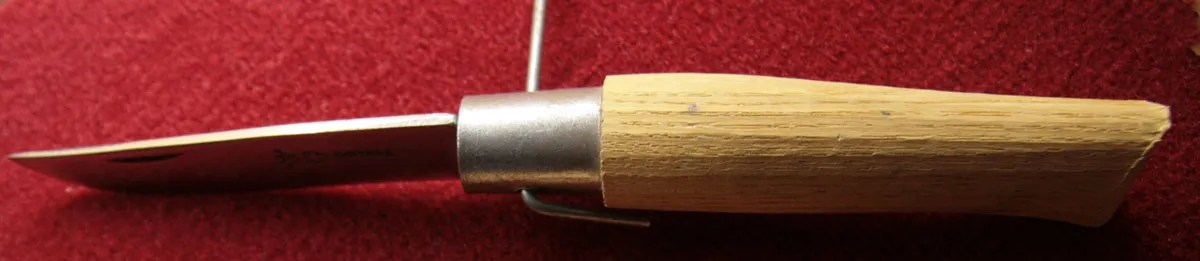 Opinel knife components showing the wooden handle, blade and steel collar
