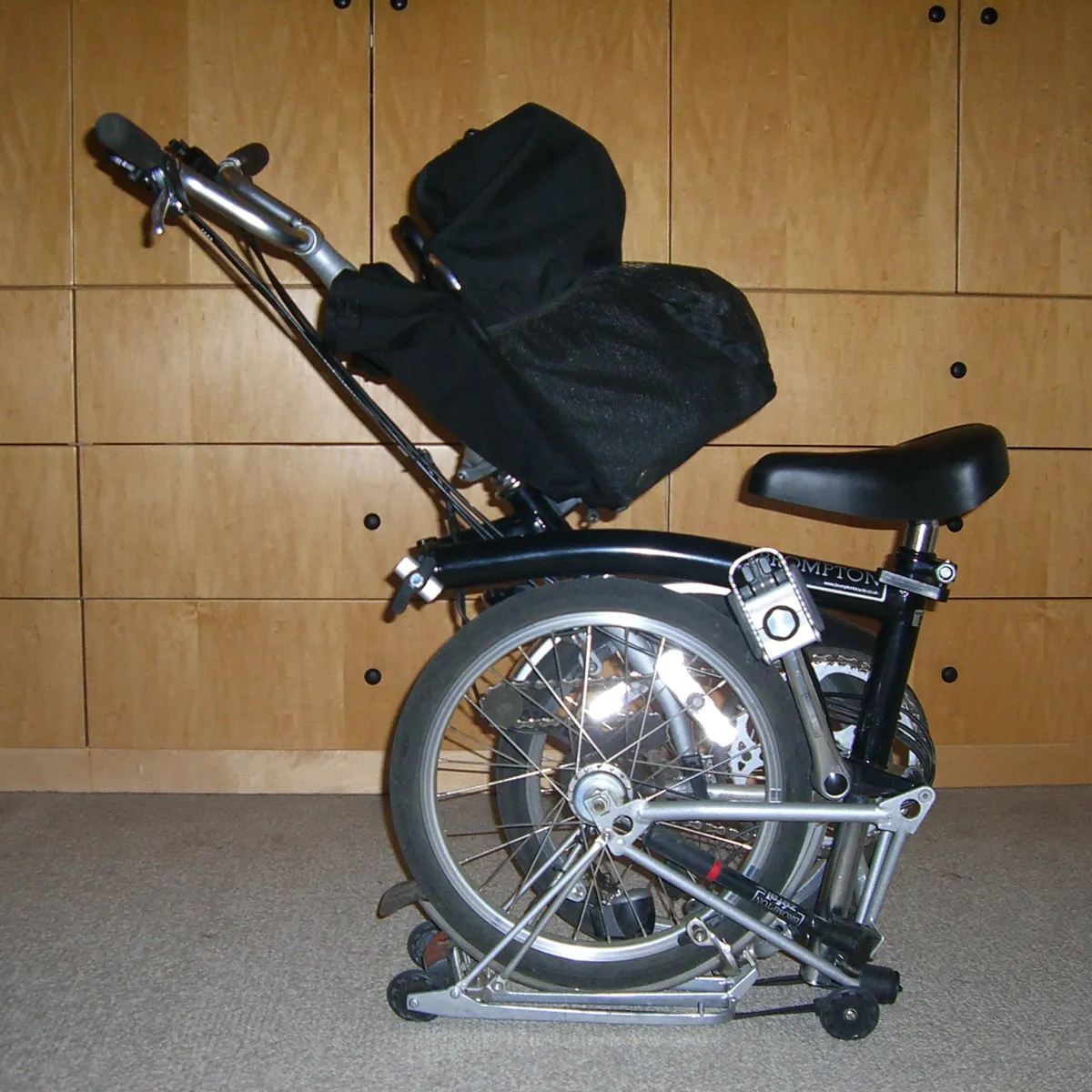 Brompton bicycle half folded with a bag mounted on the front carrier block