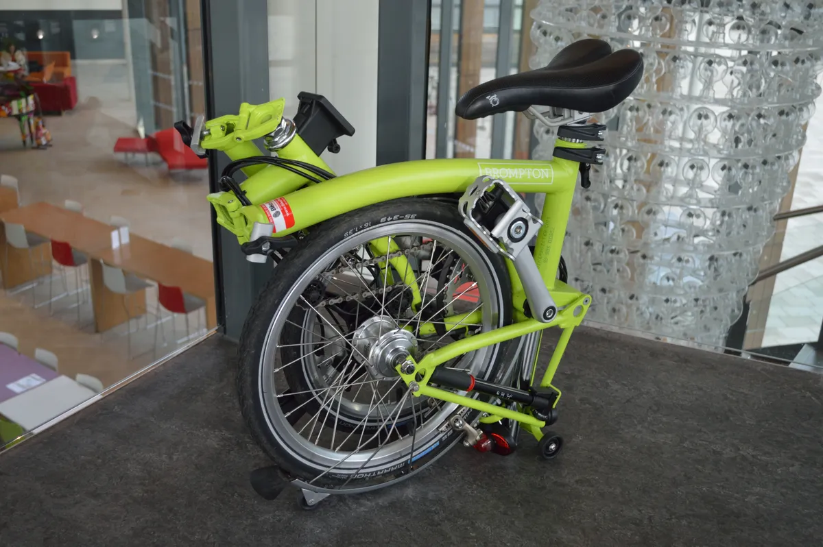 Folded Brompton bicycle standing upright on a pavement