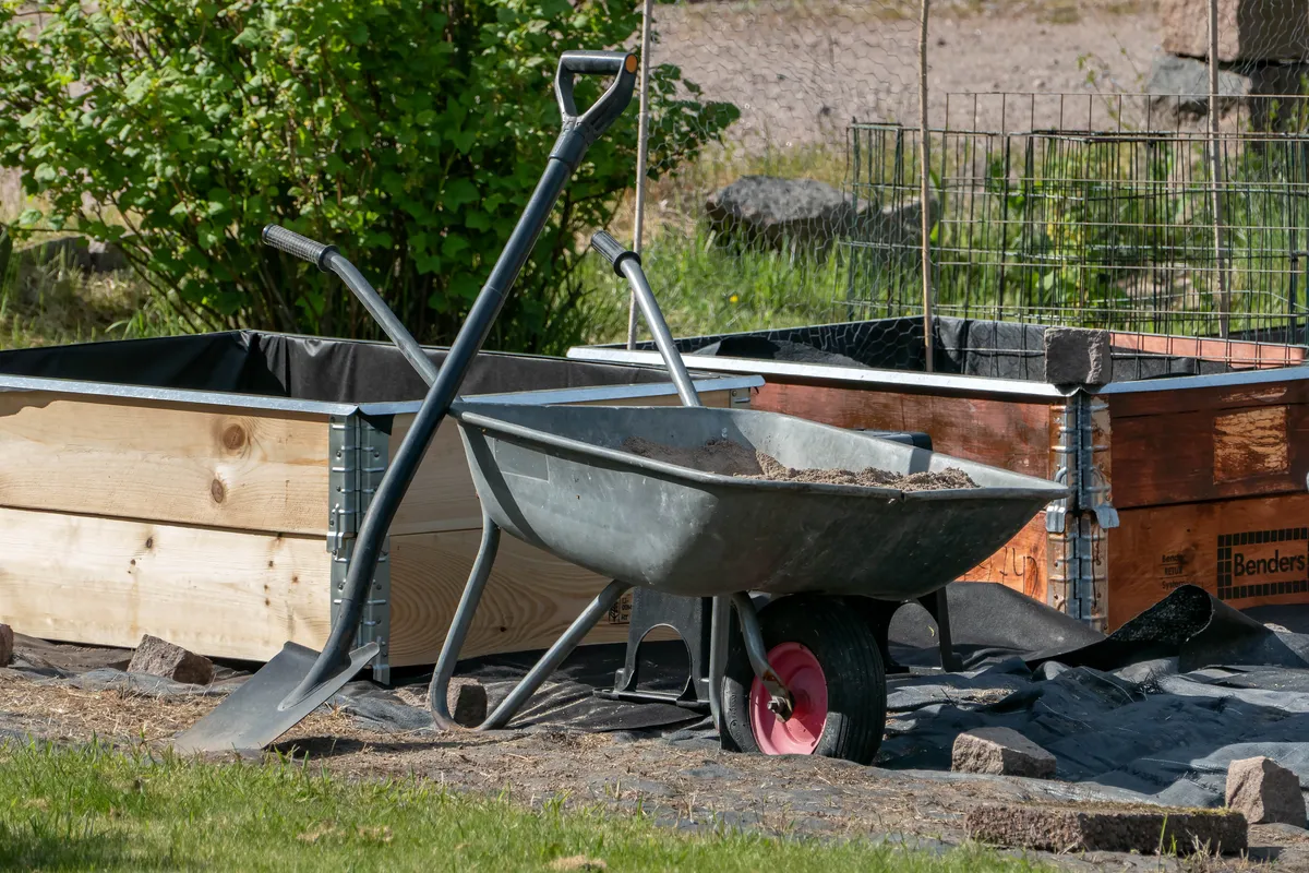 A wheelbarrow and spade left beside a garden path