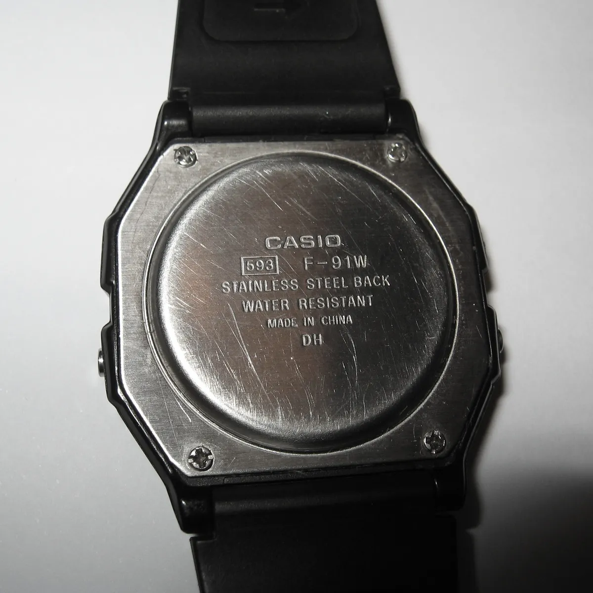 Case back of the Casio F-91W showing markings and the battery cover