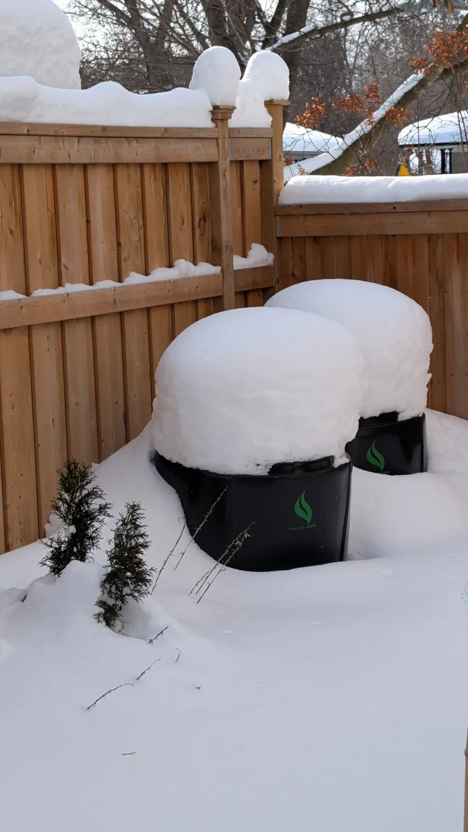 Plastic compost bins standing under snow, when decomposition effectively stops