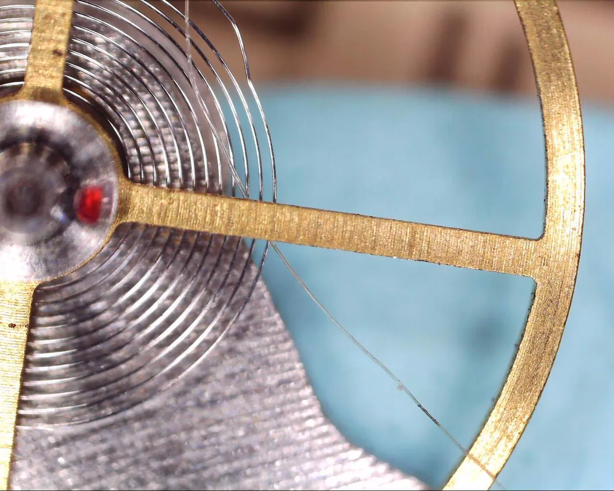 A Seiko automatic balance wheel and hairspring beside a human hair for scale