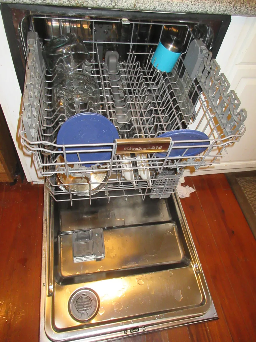 An open dishwasher showing upper and lower racks and the interior spray arms