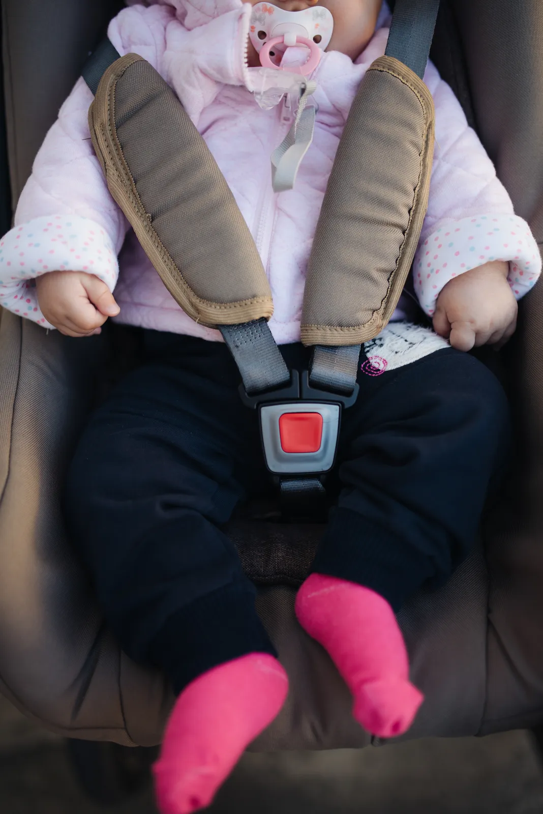 An infant securely fastened into a car seat harness
