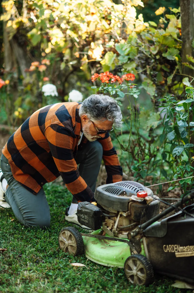 A person servicing a lawn mower in a garden