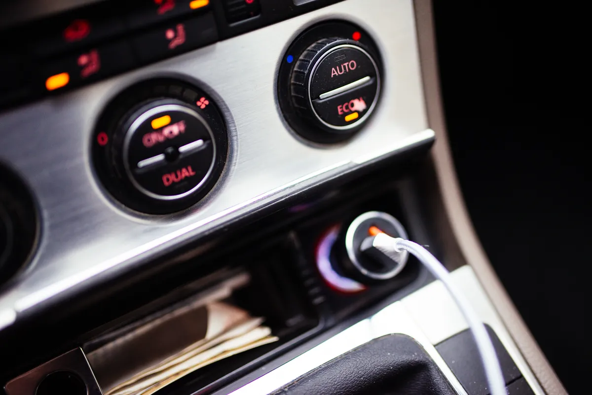 Car dashboard controls and a charging cable at night