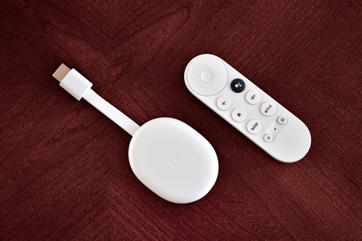 Alternate angle of the Chromecast with Google TV dongle and remote showing the HDMI connector end
