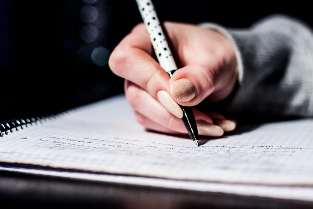 Close-up of a pen writing notes on paper, illustrating the handwriting workflow before scanning