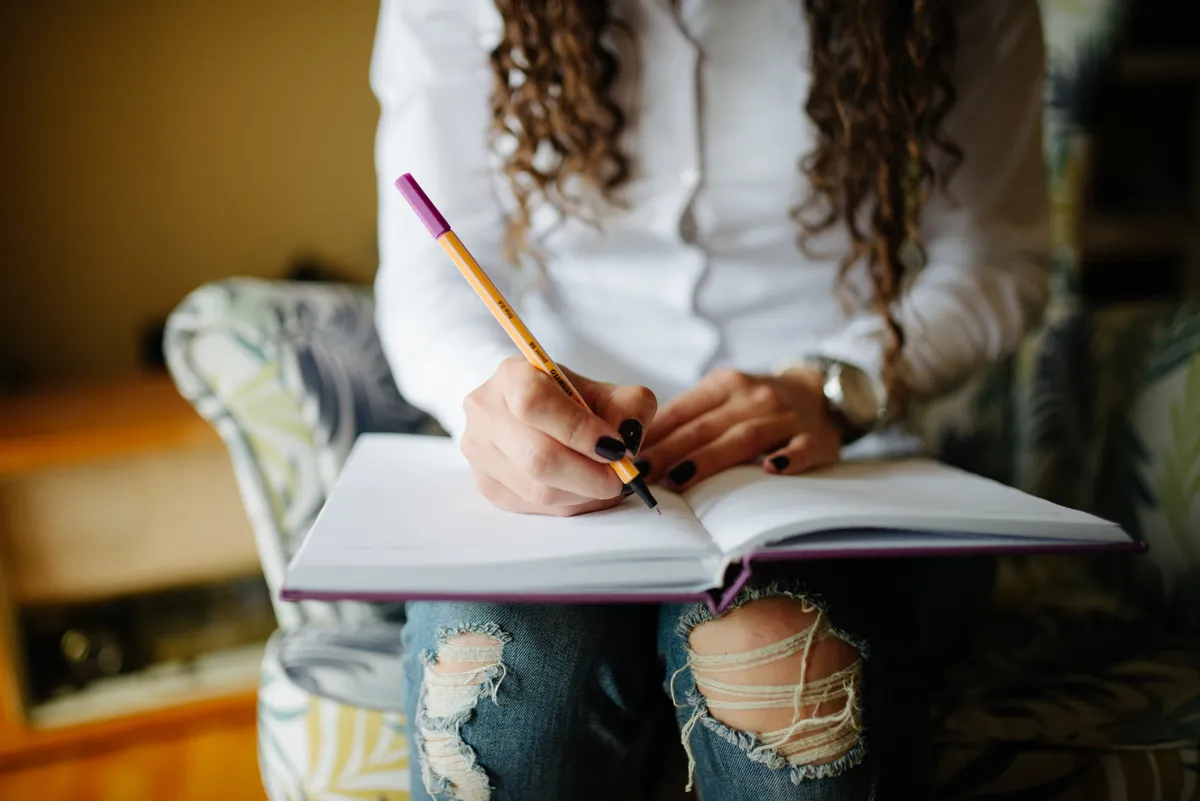 Close-up of hands writing notes in a planner-style notebook