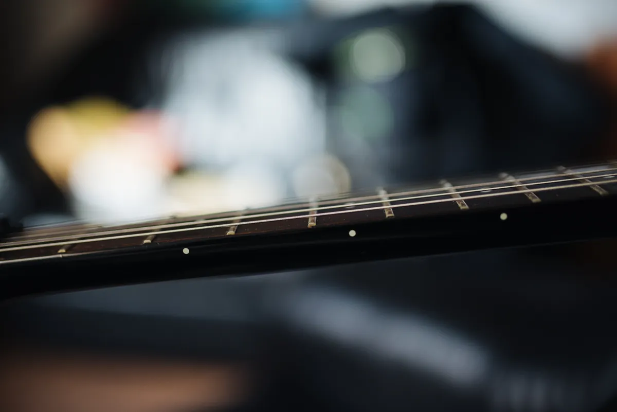 Close-up of an acoustic guitar fretboard showing string height above the frets