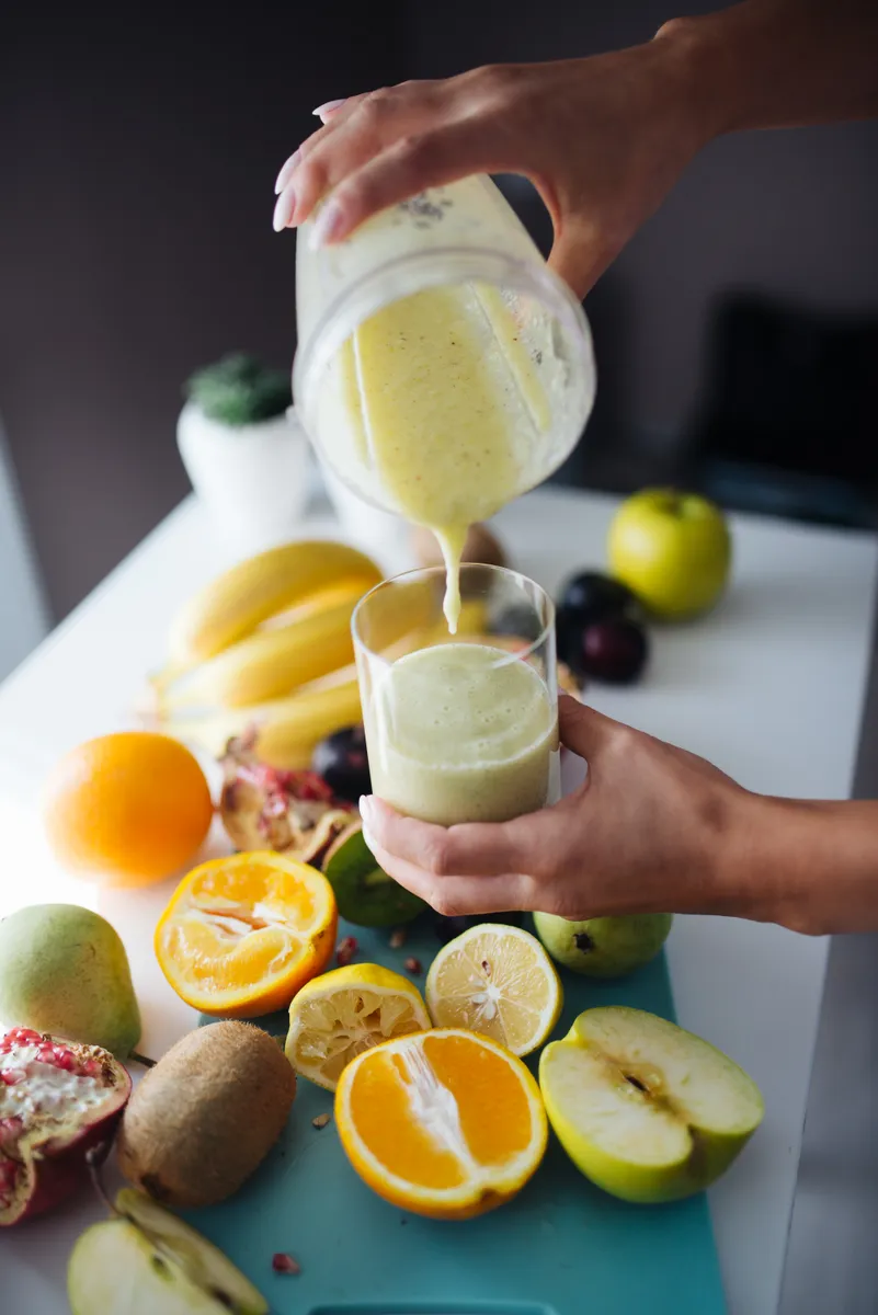 A smooth fruit smoothie being poured from a blender container into a glass