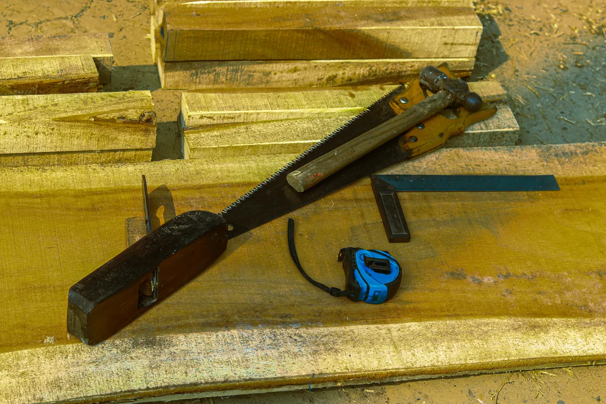 A wooden jack plane among other hand tools on stacked timber